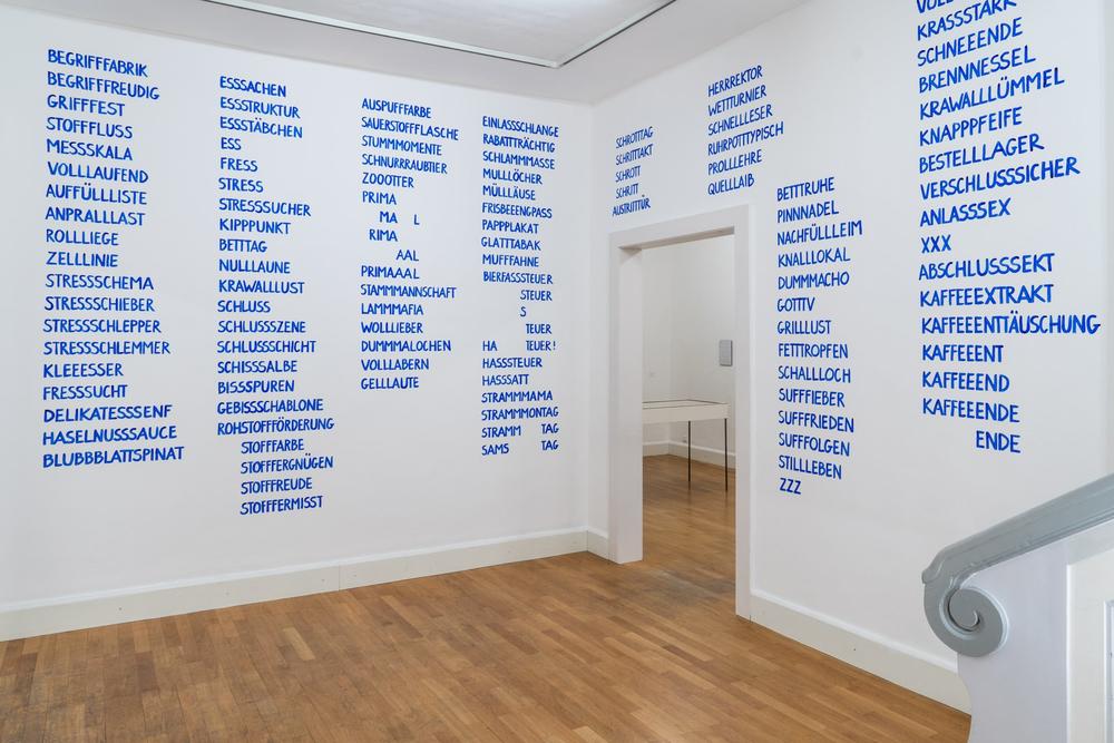 Ausstellungsansicht, Wortlisten auf den Wänden in blauen, versalen Textspalten